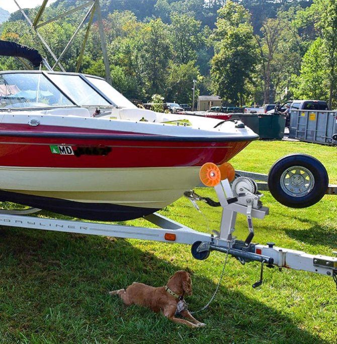 Adjustable boat trailer winch bracket with casters