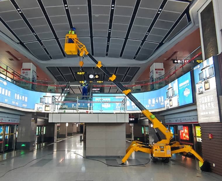 Electric spider crane equipped with a man basket for lighting installation in a subway station