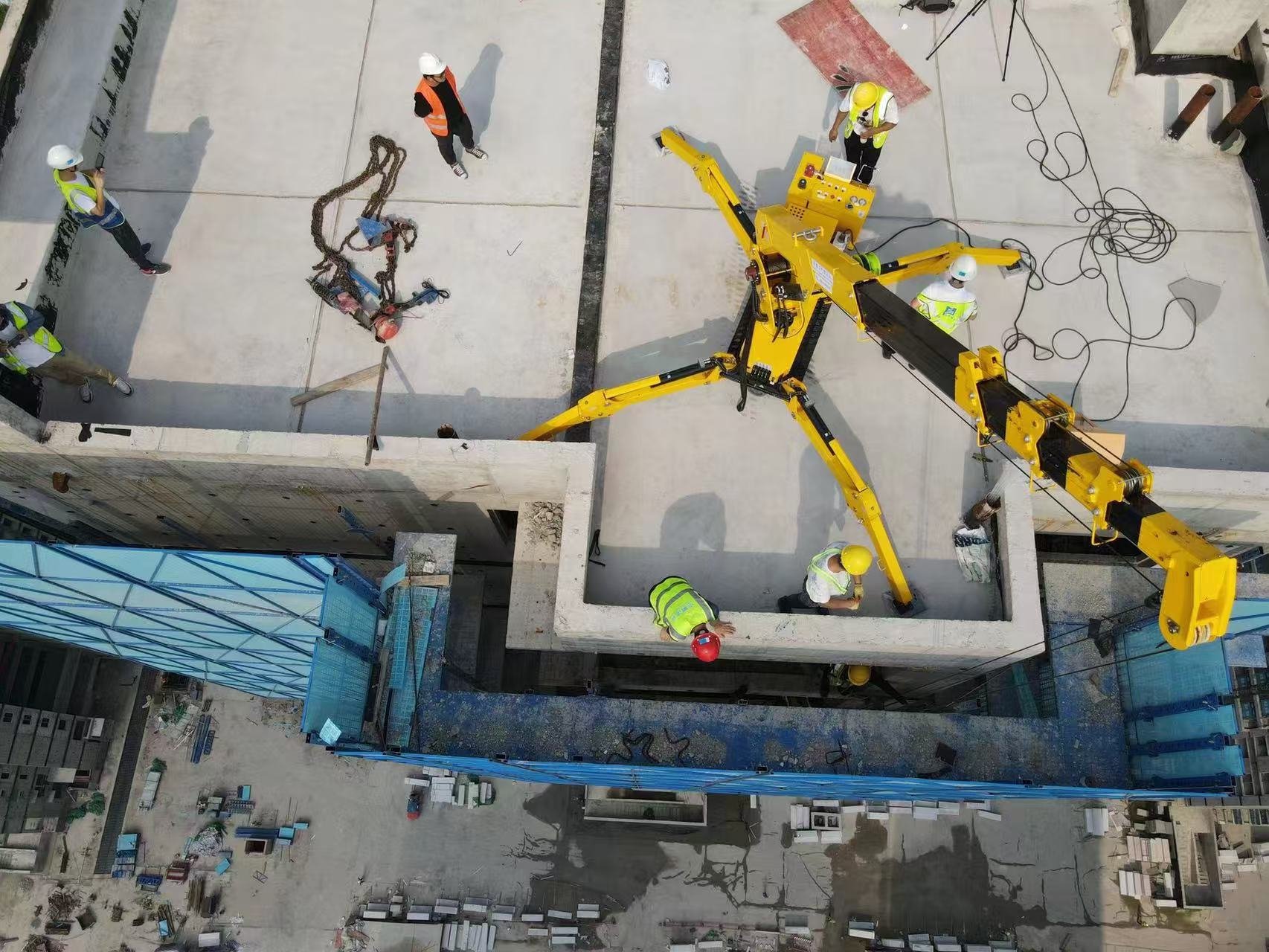 LIFTSGLT mini crawler crane operating on a rooftop construction site with outriggers deployed for narrow access lifting.