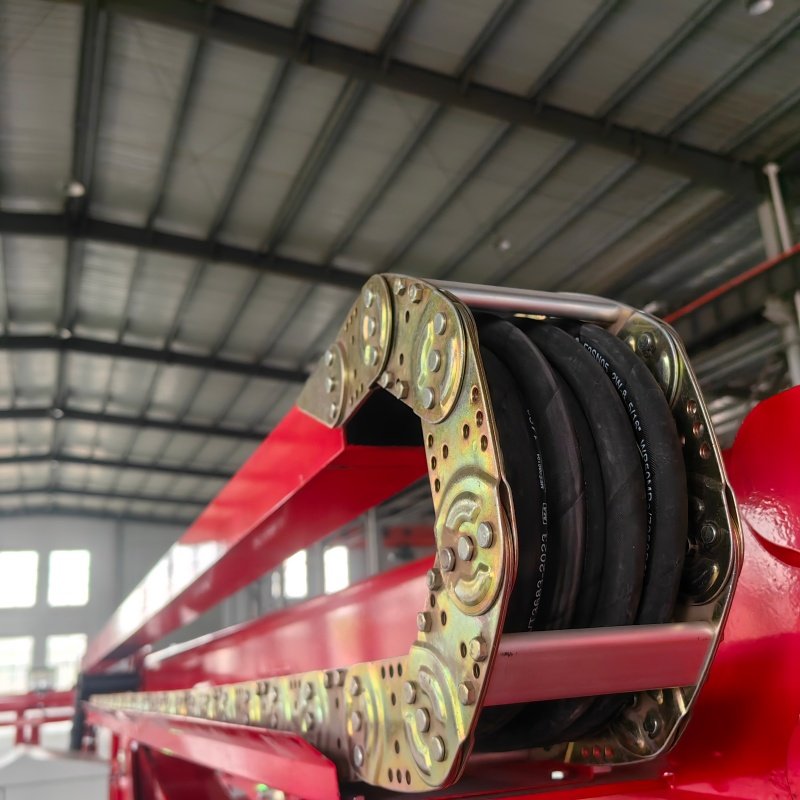 High-resolution close-up showing precision metal carrier links enforcing the minimum bend radius for internal hydraulic lines.