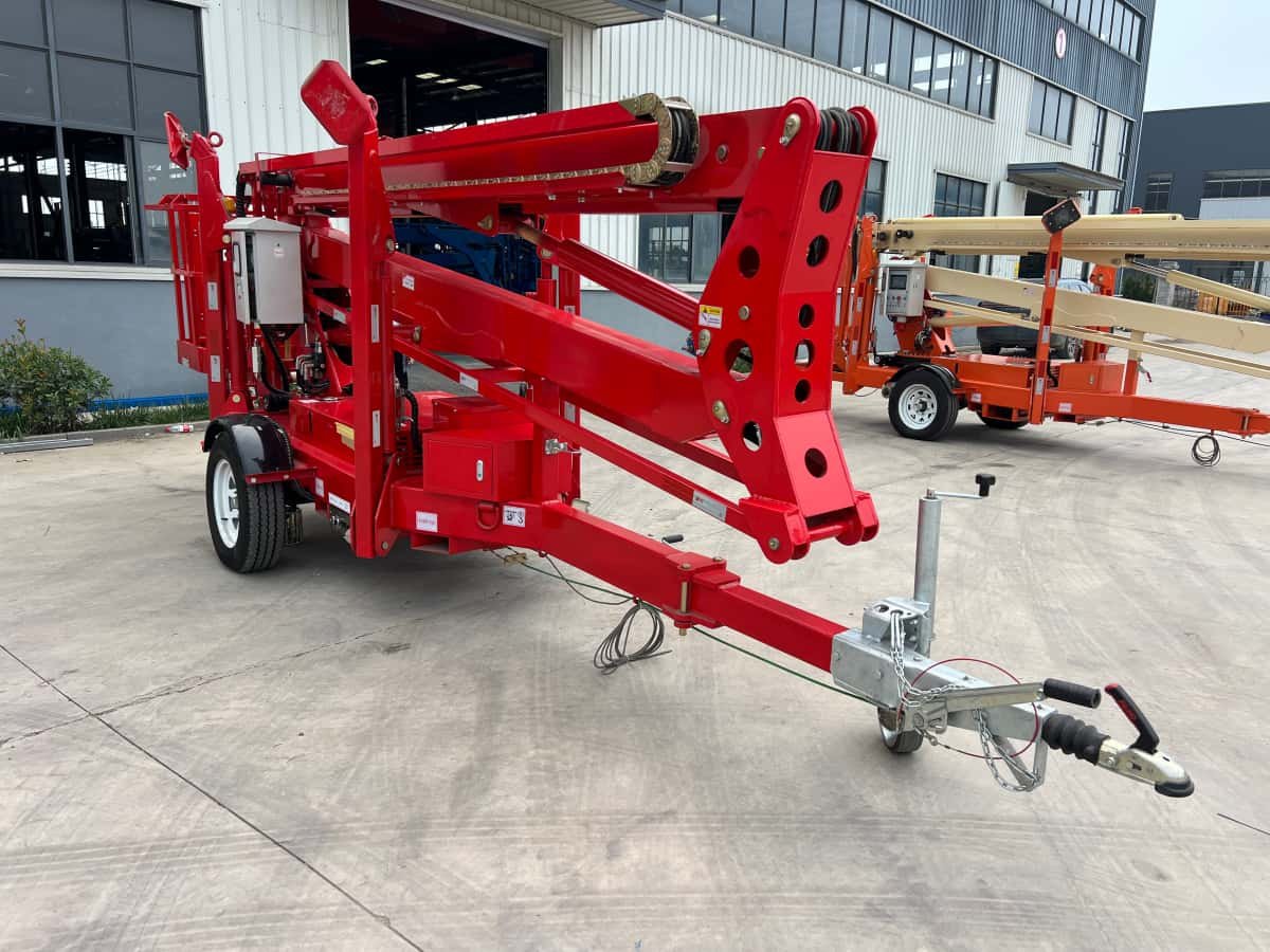 Towable articulating boom lift in stowed position showing integrated hydraulic hose carrier mounted alongside the boom arm.